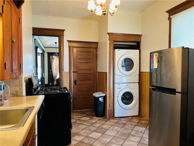 817 S 16th St, Saint Joseph, MO 64501 - laundry area with a chandelier, stacked washer / drying machine, a wainscoted wall, crown molding, and wooden walls