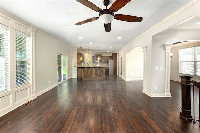 28617 W 162nd Ter, Gardner, KS 66030 - unfurnished living room with ceiling fan, ornamental molding, arched walkways, plenty of natural light, and dark wood-style floors
