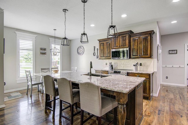 16324 S Locust St, Olathe, KS 66062 - kitchen featuring backsplash, stainless steel appliances, a center island with sink, recessed lighting, and a breakfast bar