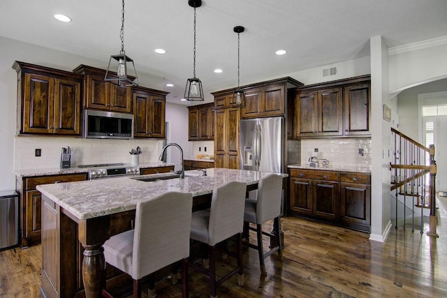 16324 S Locust St, Olathe, KS 66062 - kitchen with stainless steel appliances, decorative backsplash, recessed lighting, a center island with sink, and dark wood-type flooring