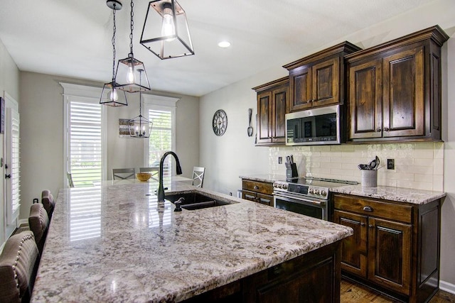 16324 S Locust St, Olathe, KS 66062 - kitchen featuring appliances with stainless steel finishes, light stone counters, backsplash, dark brown cabinetry, and wood finished floors