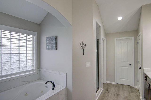 16324 S Locust St, Olathe, KS 66062 - bathroom with vanity, healthy amount of natural light, a tub with jets, wood finished floors, and lofted ceiling