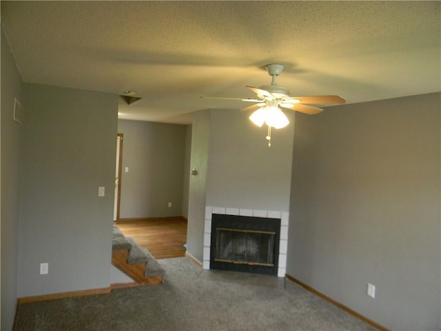 730 SE 10th St, Lees Summit, MO 64081 - unfurnished living room featuring a tiled fireplace, ceiling fan, carpet flooring, and a textured ceiling