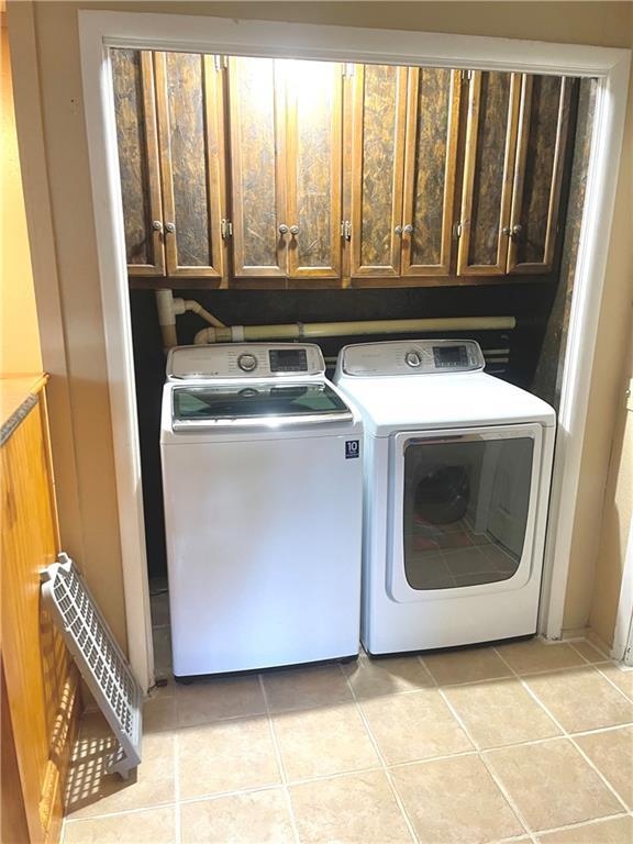 177 1150th St, Humboldt, KS 66748 - washroom featuring washing machine and clothes dryer, cabinet space, and light tile patterned floors