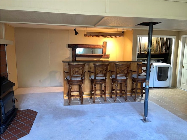 177 1150th St, Humboldt, KS 66748 - indoor dry bar with a wood stove, carpet, washer / dryer, and tile patterned flooring