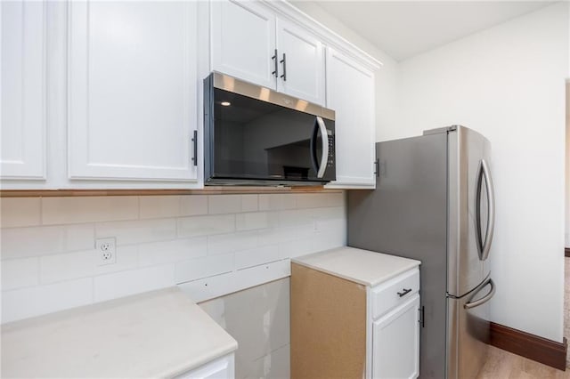 308 W Pine St, Cherokee, KS 66724 - kitchen with appliances with stainless steel finishes, light countertops, white cabinetry, tasteful backsplash, and light wood-type flooring