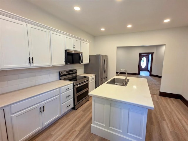 308 W Pine St, Cherokee, KS 66724 - kitchen featuring appliances with stainless steel finishes, tasteful backsplash, white cabinetry, light countertops, and a kitchen island with sink