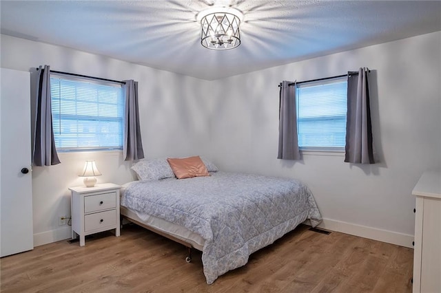 2439 Jasu Dr, Lawrence, KS 66046 - bedroom with multiple windows, wood finished floors, and a chandelier