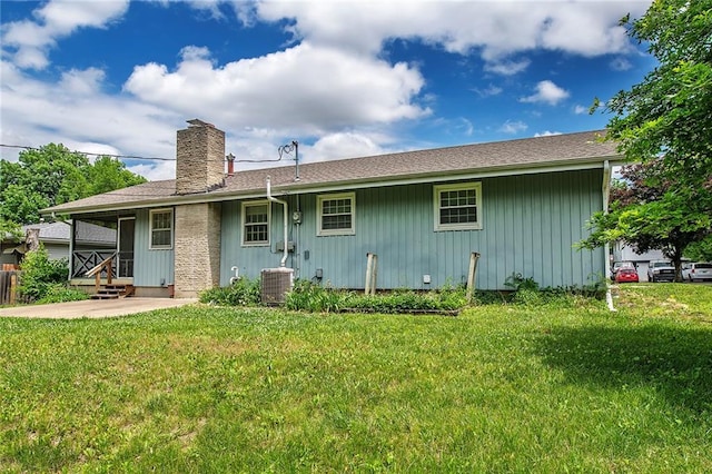 2439 Jasu Dr, Lawrence, KS 66046 - rear view of property with board and batten siding, a yard, a chimney, a patio area, and roof with shingles
