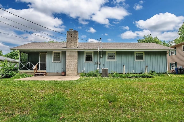 2439 Jasu Dr, Lawrence, KS 66046 - back of house with board and batten siding, a patio area, a chimney, and a lawn