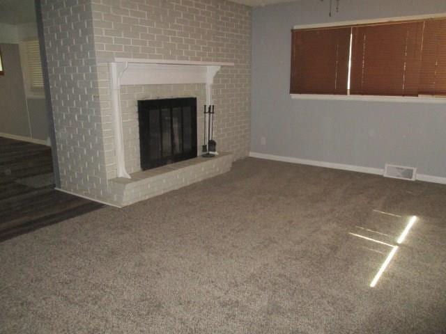 unfurnished living room featuring a fireplace and dark colored carpet