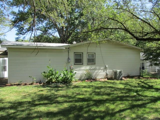 view of side of property with central AC and a lawn