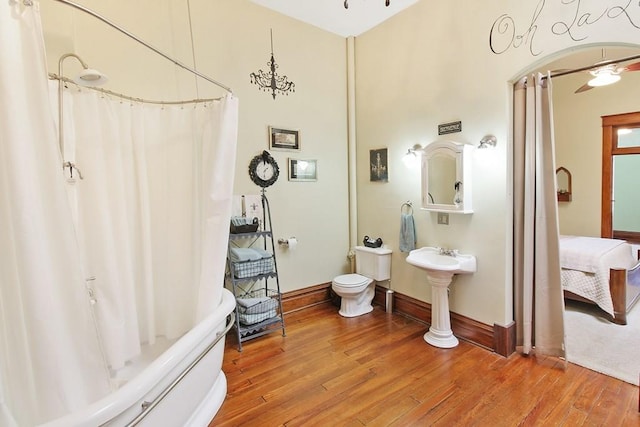 bathroom with ceiling fan, toilet, hardwood / wood-style flooring, and shower / bath combo