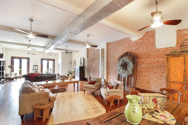 living room with french doors, brick wall, hardwood / wood-style flooring, beam ceiling, and ceiling fan