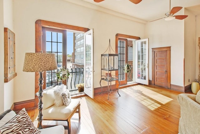 sitting room with a high ceiling, ceiling fan, and light hardwood / wood-style floors