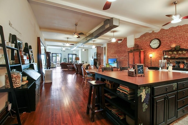 interior space featuring ceiling fan, beam ceiling, and brick wall