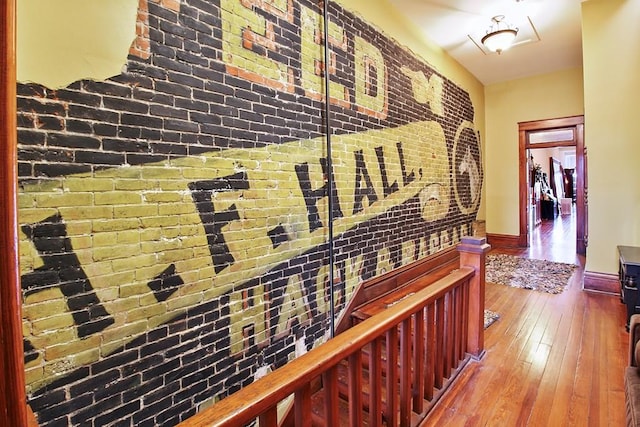 hall with brick wall and wood-type flooring