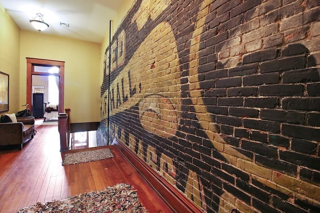 interior space with brick wall and dark hardwood / wood-style flooring