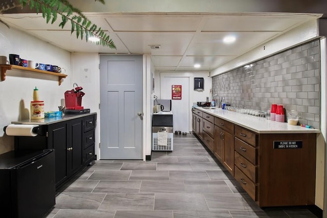 kitchen with backsplash, sink, light tile floors, and a drop ceiling