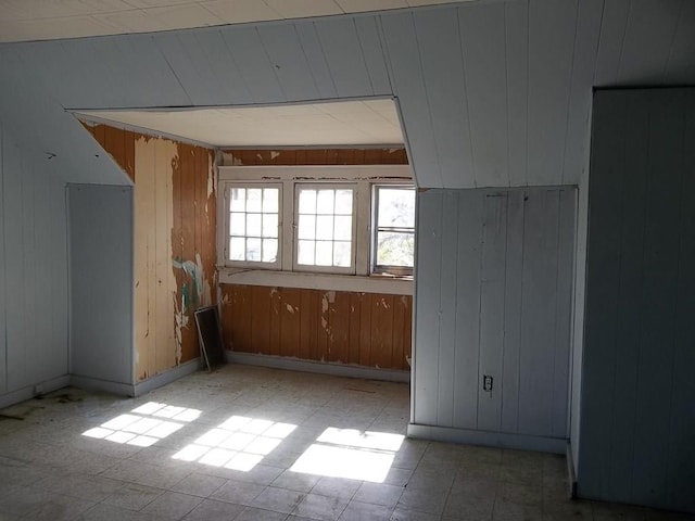 bonus room featuring tile floors and wood walls