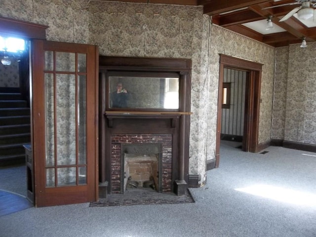 unfurnished living room with ceiling fan, carpet floors, and beam ceiling