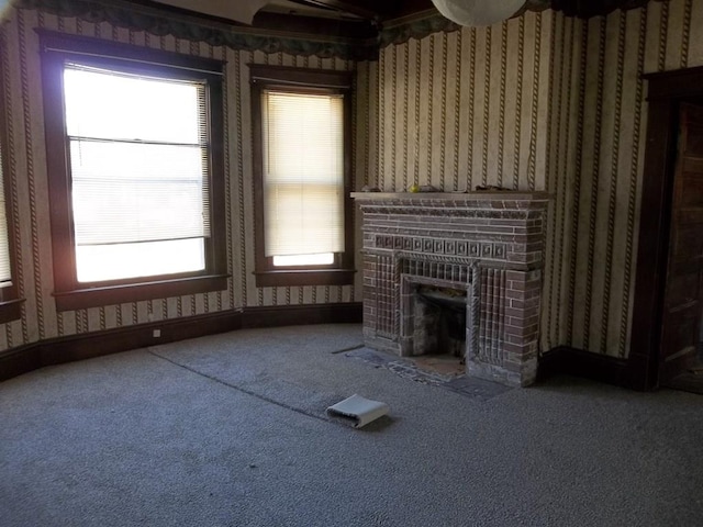 unfurnished living room with plenty of natural light, a fireplace, and carpet