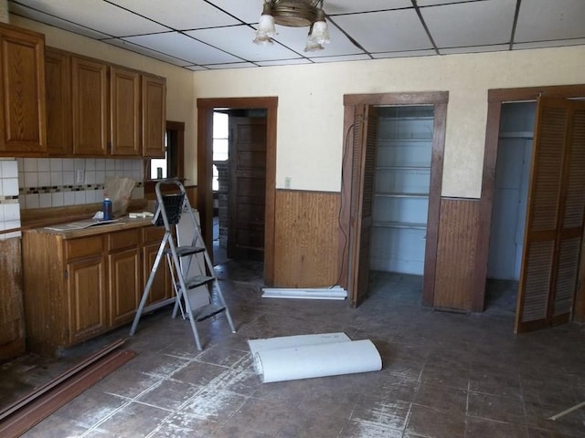 kitchen featuring tasteful backsplash, dark tile flooring, and a drop ceiling