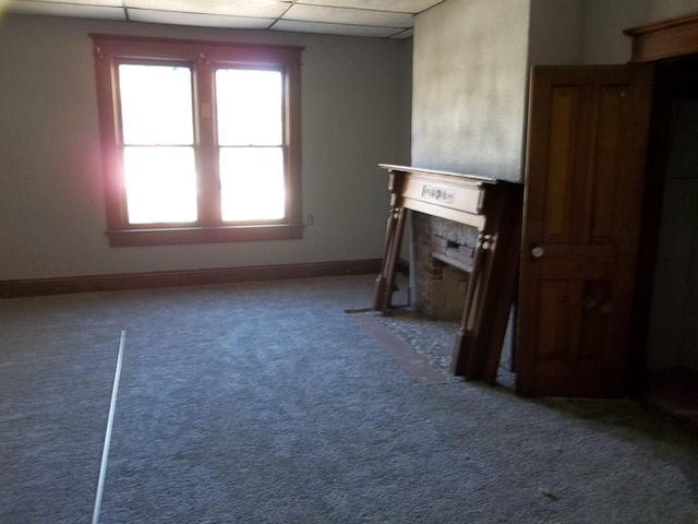 unfurnished living room featuring a wealth of natural light, carpet flooring, and a drop ceiling