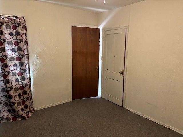 spare room with dark carpet