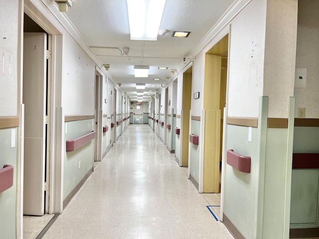 hall with a textured ceiling and light tile floors