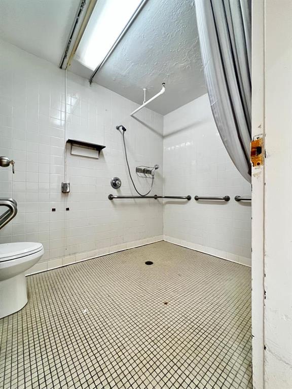 bathroom featuring tile flooring, tile walls, and toilet