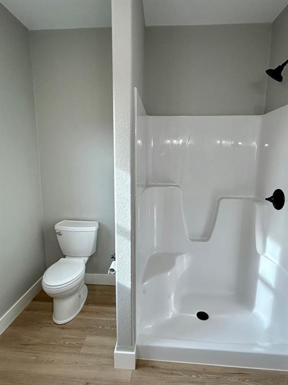 bathroom featuring a shower, wood-type flooring, and toilet