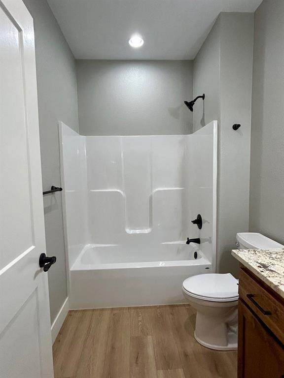 full bathroom featuring washtub / shower combination, hardwood / wood-style floors, vanity, and toilet