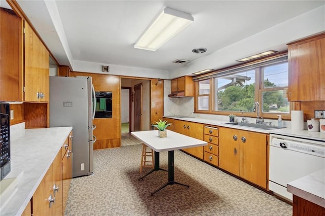 kitchen featuring sink, stainless steel refrigerator, white dishwasher, decorative backsplash, and oven