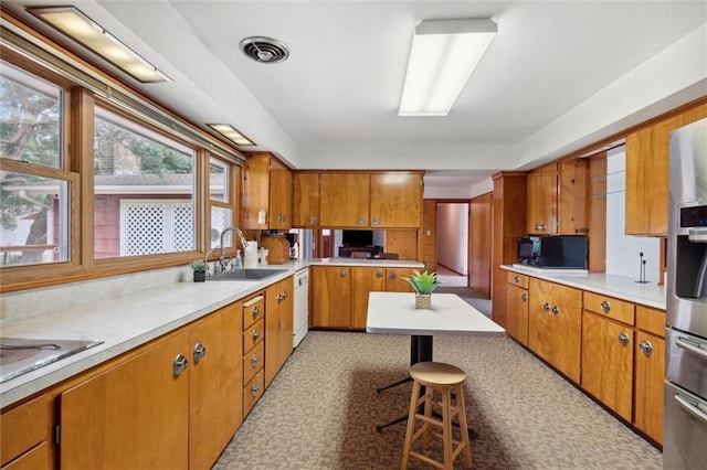 kitchen with sink, stainless steel fridge, dishwasher, and a kitchen bar