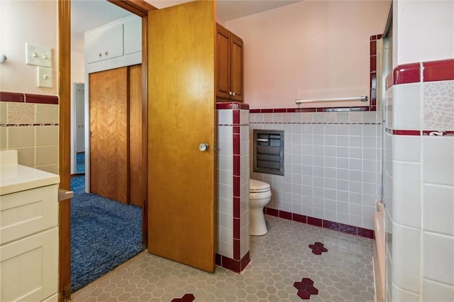 bathroom with vanity, tile walls, and toilet