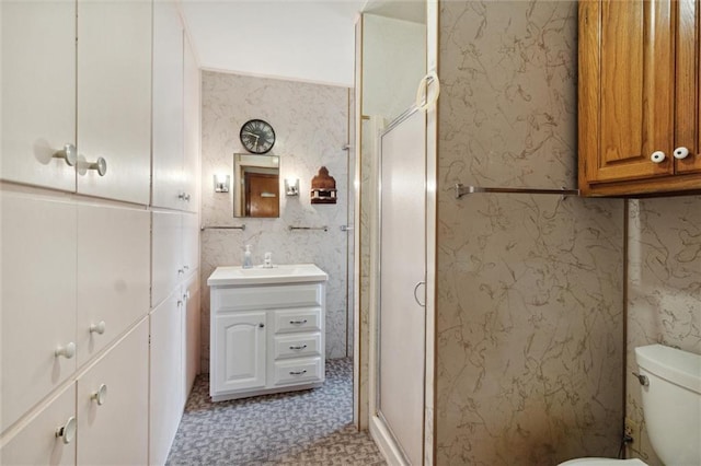 bathroom featuring vanity, a shower with shower door, and toilet