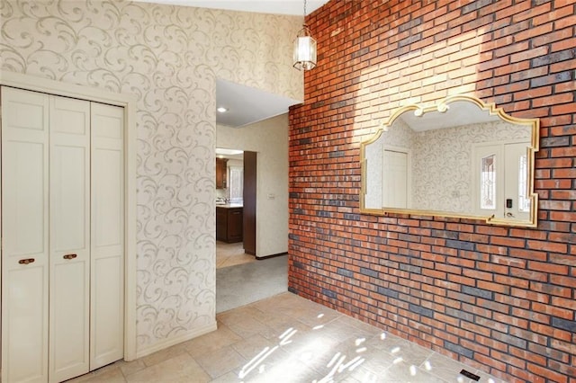 interior space featuring light tile patterned floors, brick wall, and decorative light fixtures