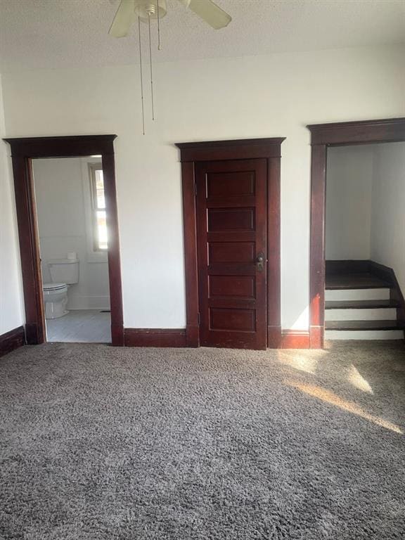 unfurnished bedroom with carpet flooring, ensuite bathroom, ceiling fan, and a textured ceiling