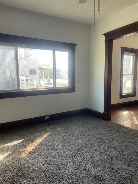 carpeted spare room with ceiling fan and a textured ceiling