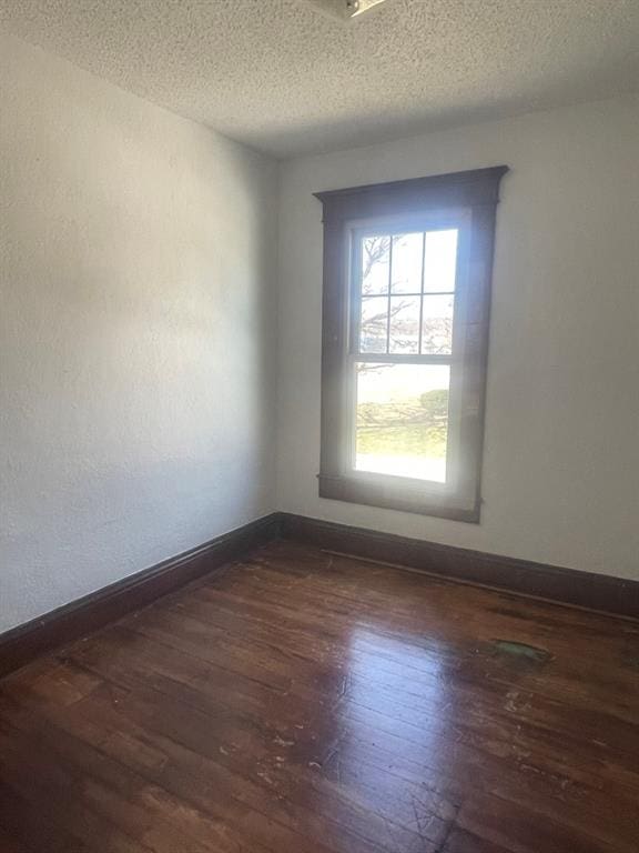 spare room with a textured ceiling and dark wood-type flooring