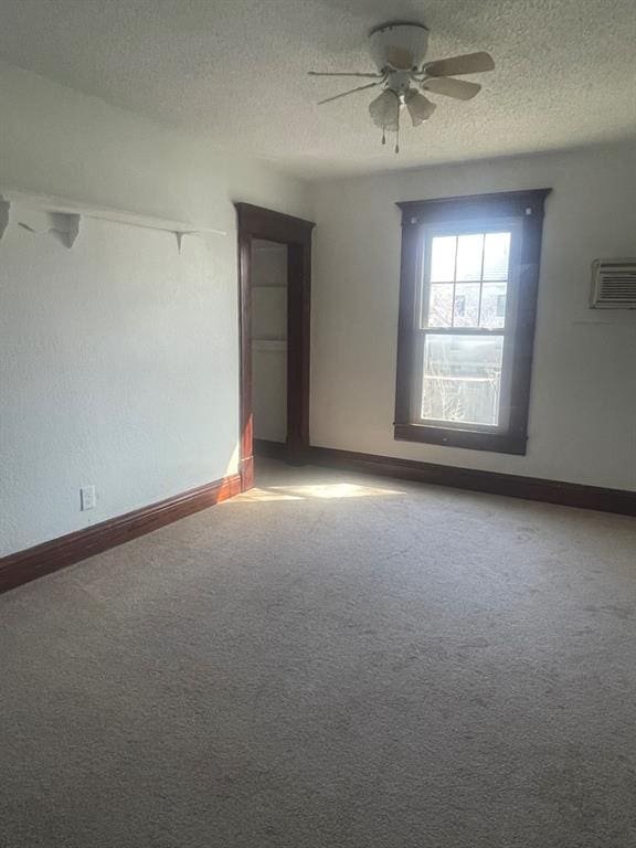 unfurnished room featuring carpet, ceiling fan, a textured ceiling, and a wall unit AC