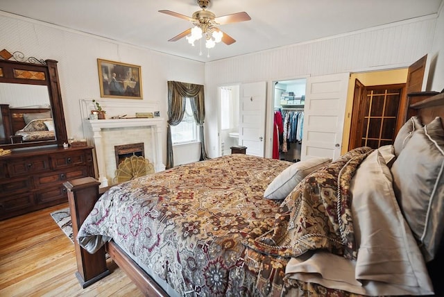 bedroom with ornamental molding, a spacious closet, ceiling fan, light wood-type flooring, and a closet