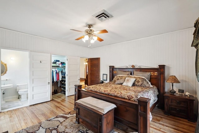 bedroom featuring ensuite bathroom, a walk in closet, a closet, ceiling fan, and light hardwood / wood-style floors