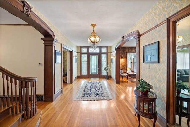 foyer entrance featuring a healthy amount of sunlight, decorative columns, and light hardwood / wood-style flooring