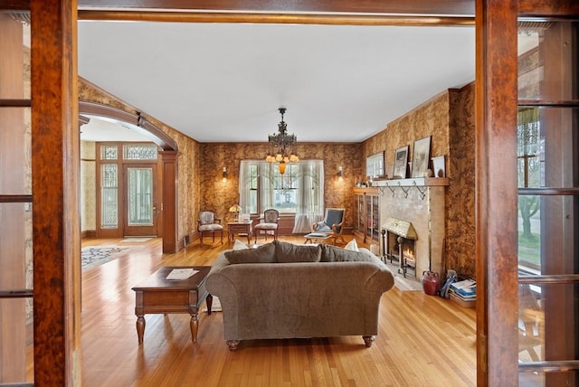 living room with a large fireplace, a chandelier, and light hardwood / wood-style floors