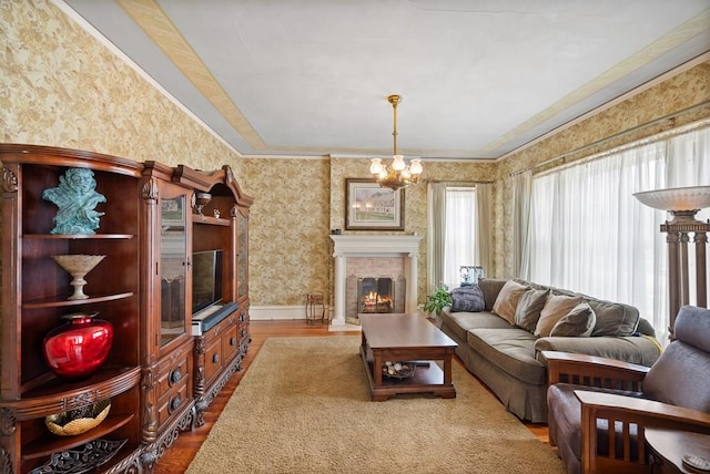 living room with ornamental molding, a brick fireplace, hardwood / wood-style floors, and a chandelier