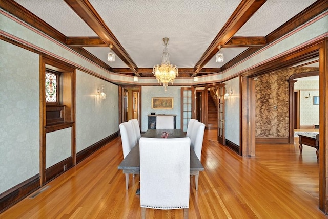 dining room with a textured ceiling, a notable chandelier, beam ceiling, and light hardwood / wood-style flooring