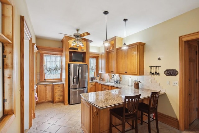 kitchen with sink, a breakfast bar area, stainless steel fridge with ice dispenser, kitchen peninsula, and decorative backsplash