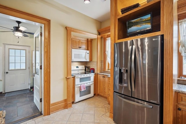 kitchen featuring light stone counters, white appliances, a healthy amount of sunlight, and backsplash